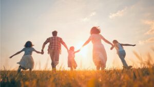 Familie cu trei copii alergând pe câmp la apus, Munții Ciucaș